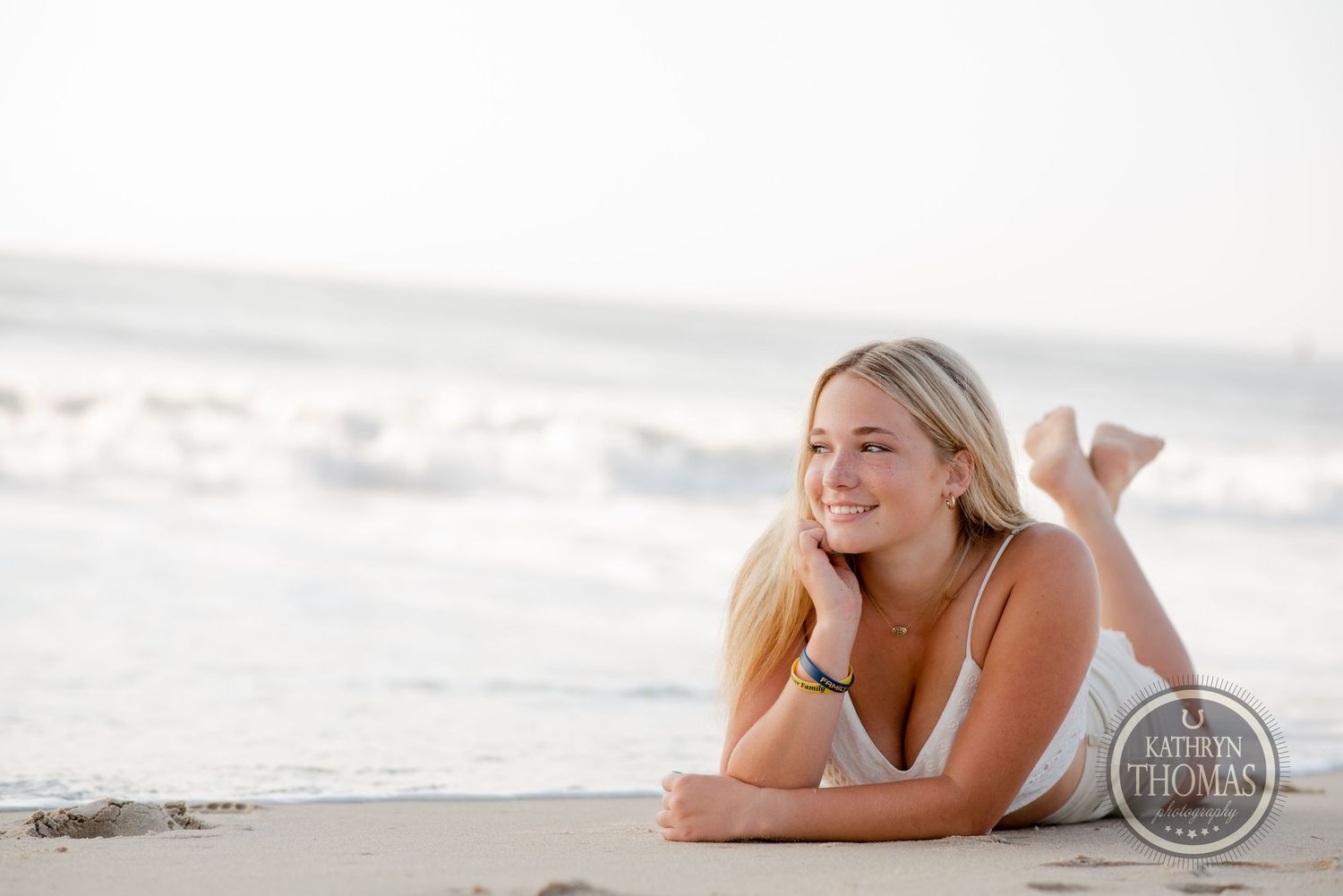 Casual beach photo of someone lying on white sand with ocean waves in the background.