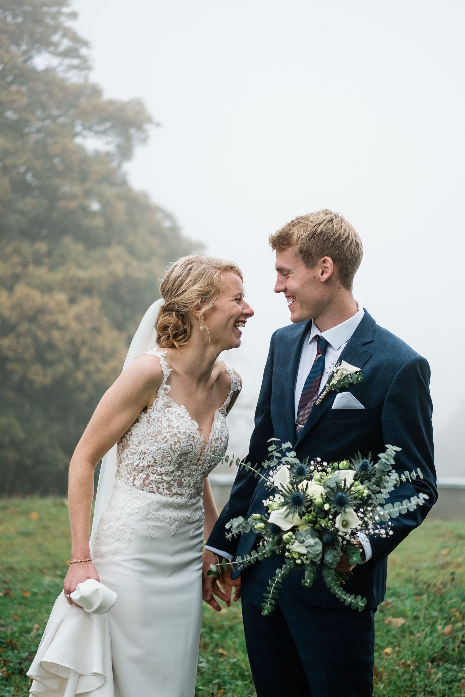 A joyful wedding moment shared between a couple amid foggy autumn scenery.