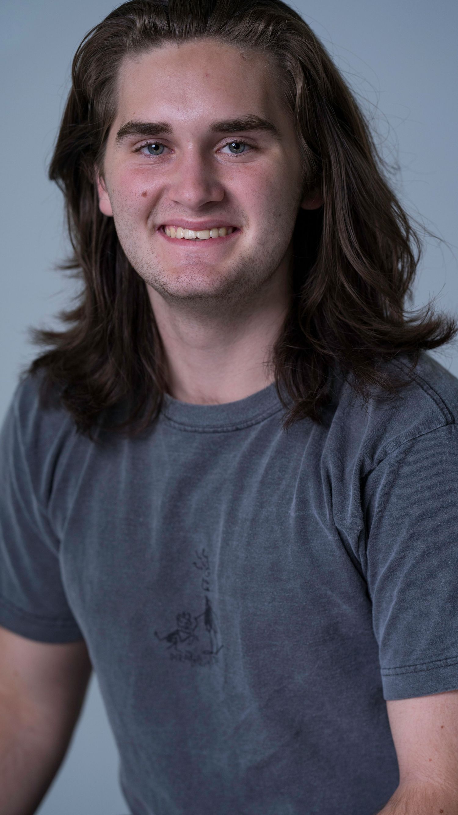 Young man with long hair and grey t shirt.  Headshot at the Blendz Media Video Production Actors Workshop