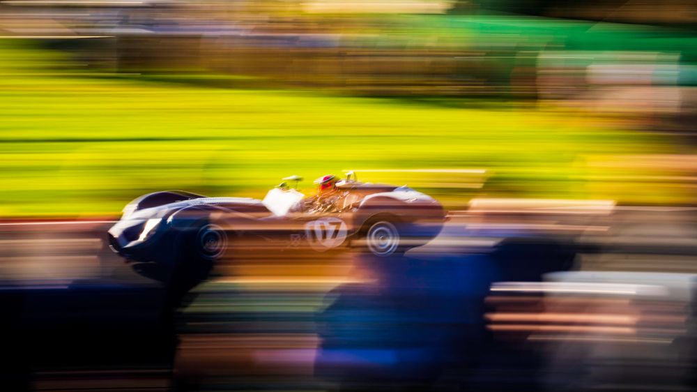 Motion-blurred race cars creating colorful streaks on a racing circuit.