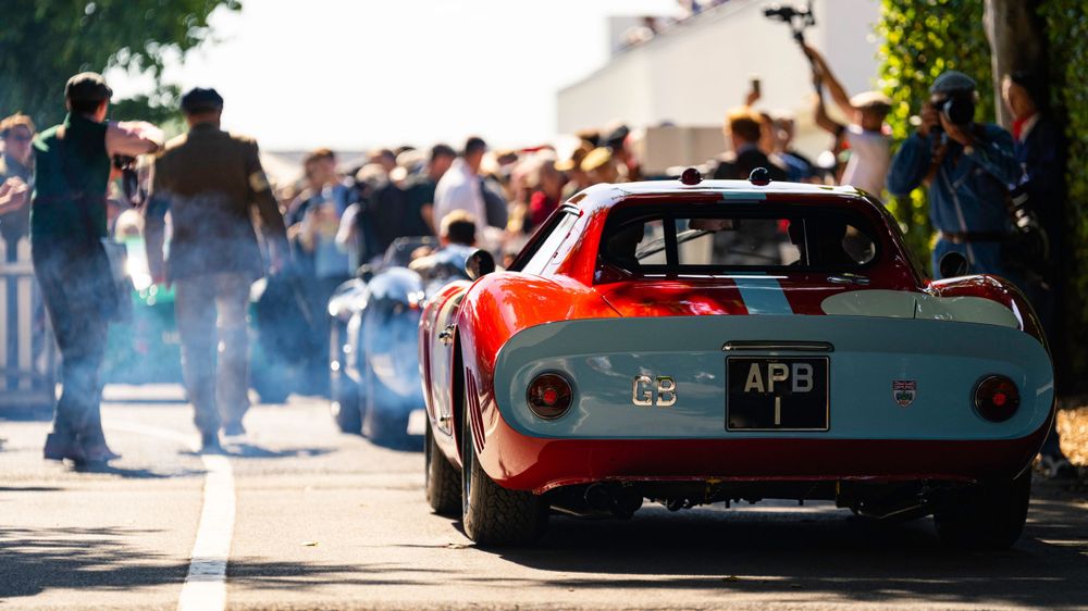 Vintage sports cars lined up at an outdoor classic car show with spectators.