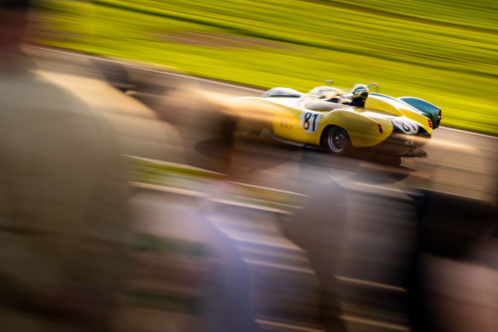 Racing cars in motion create dramatic streaks of color and movement on a racetrack.