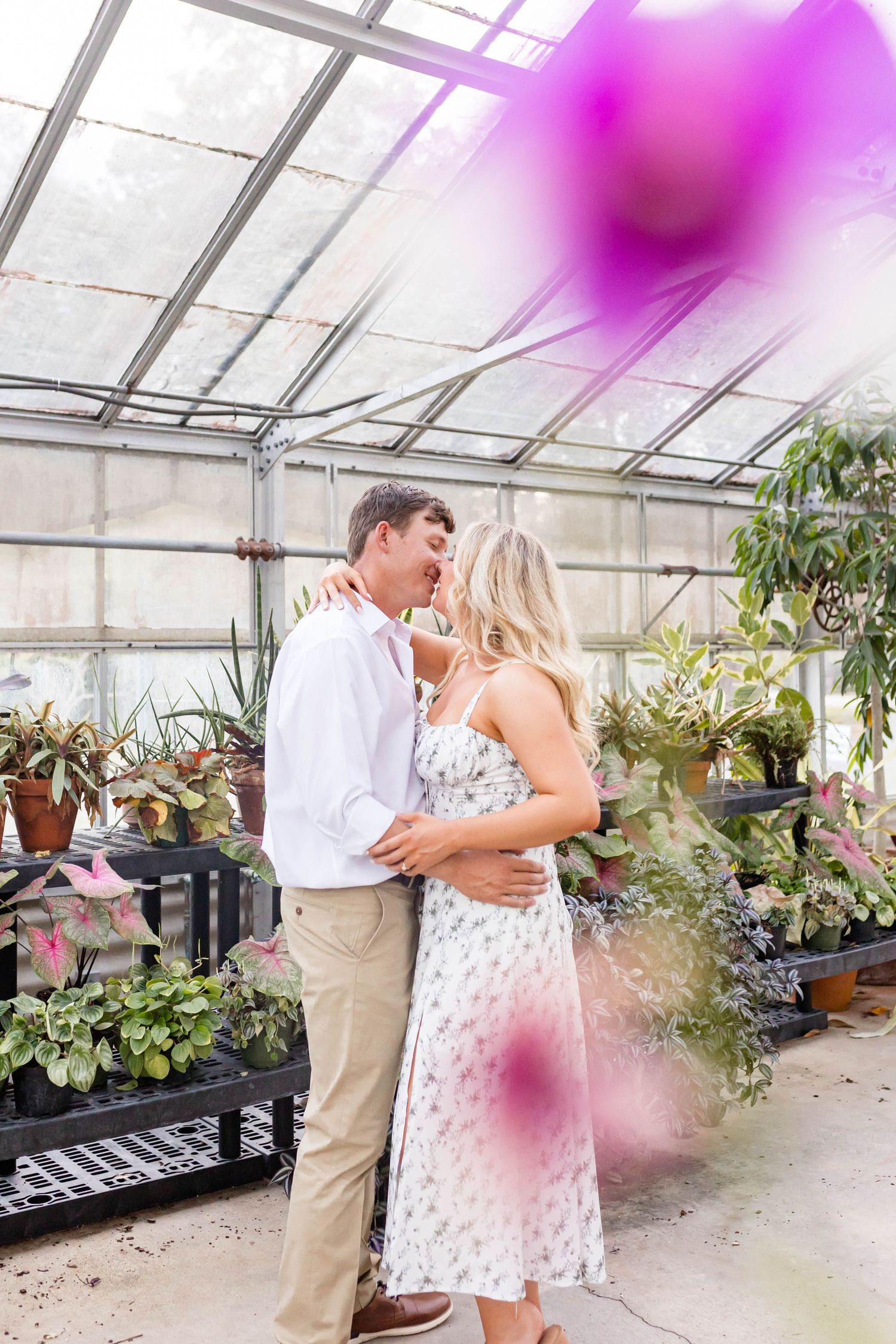 man and woman embrace and kiss in a greenhouse in Baton Rouge, LA