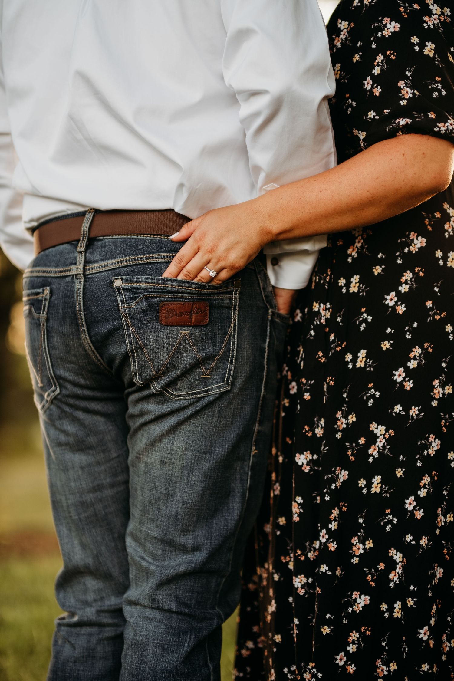 Woman has her hand in man's back Wrangler pocket showing her engagment ring during an engagment session in Arkansas.