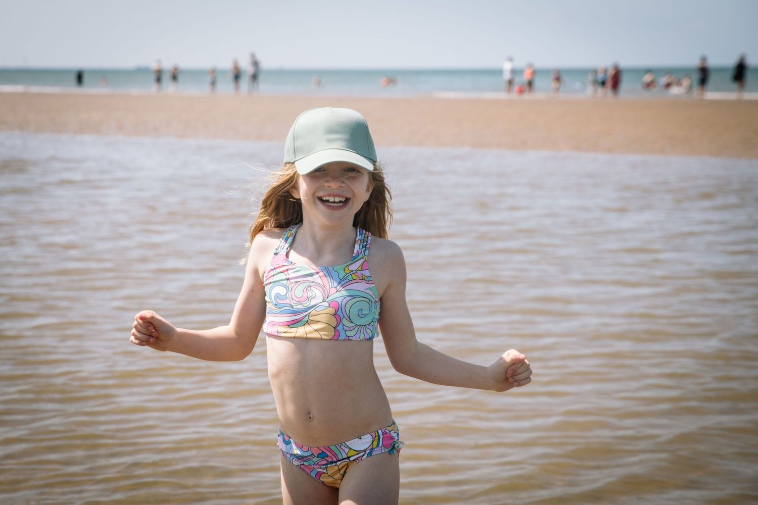 A sunny day at the beach with swimmers visible in the distance.