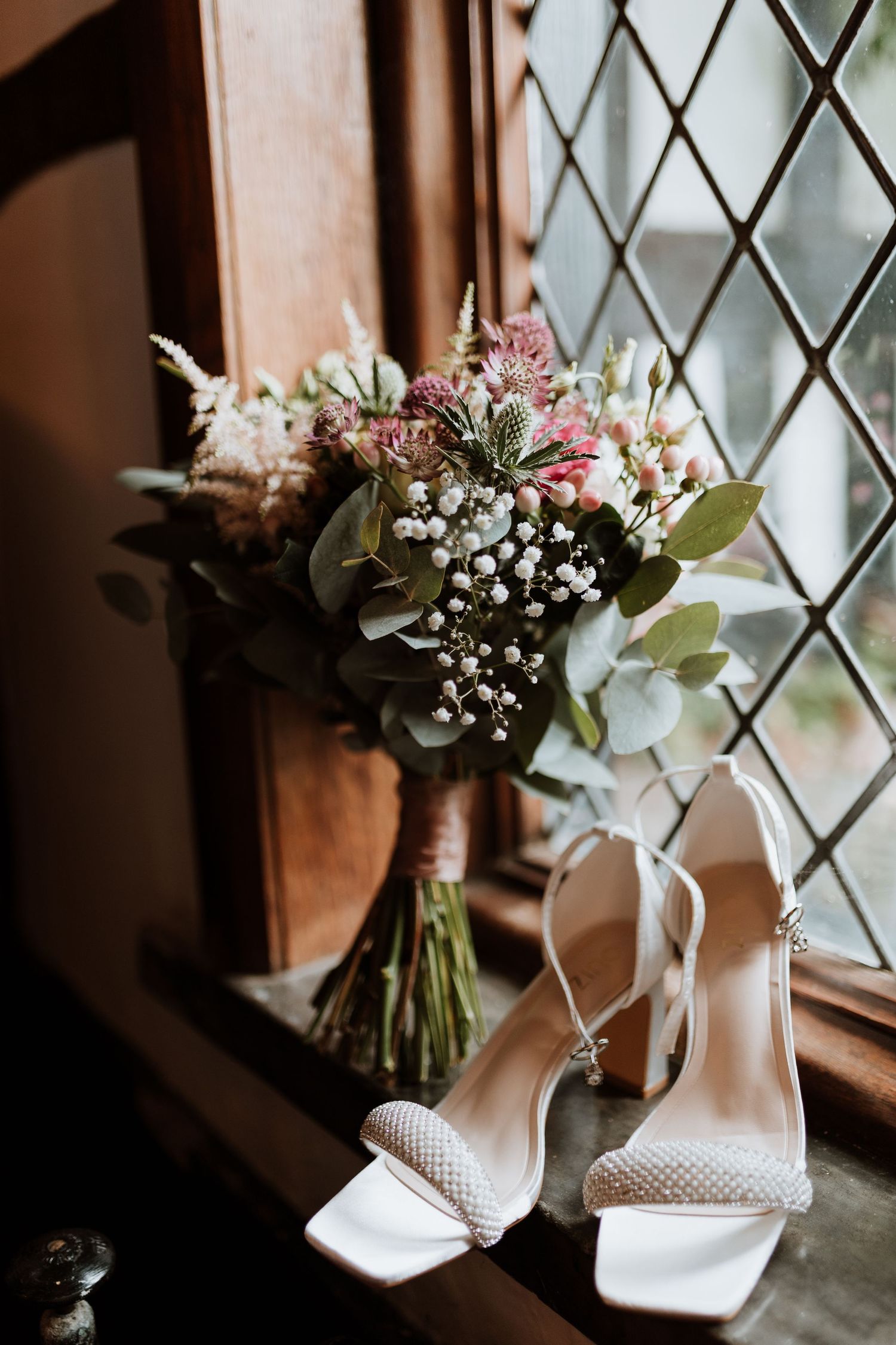 Wedding bouquet and shoes in the window of Maes Mawr Hall