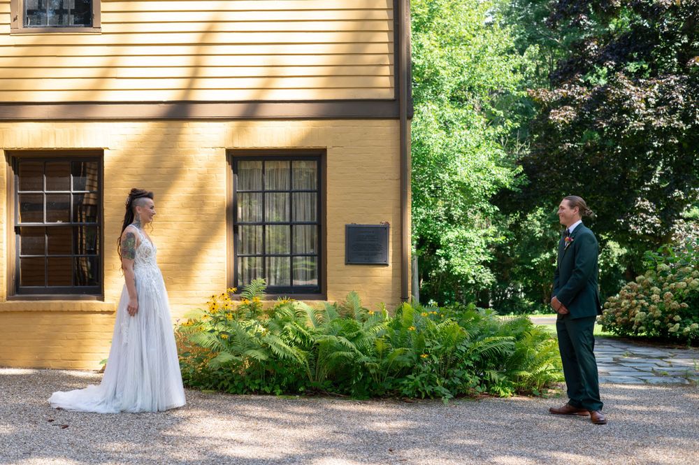 Wedding couple shares first look moment in front of yellow historic building.