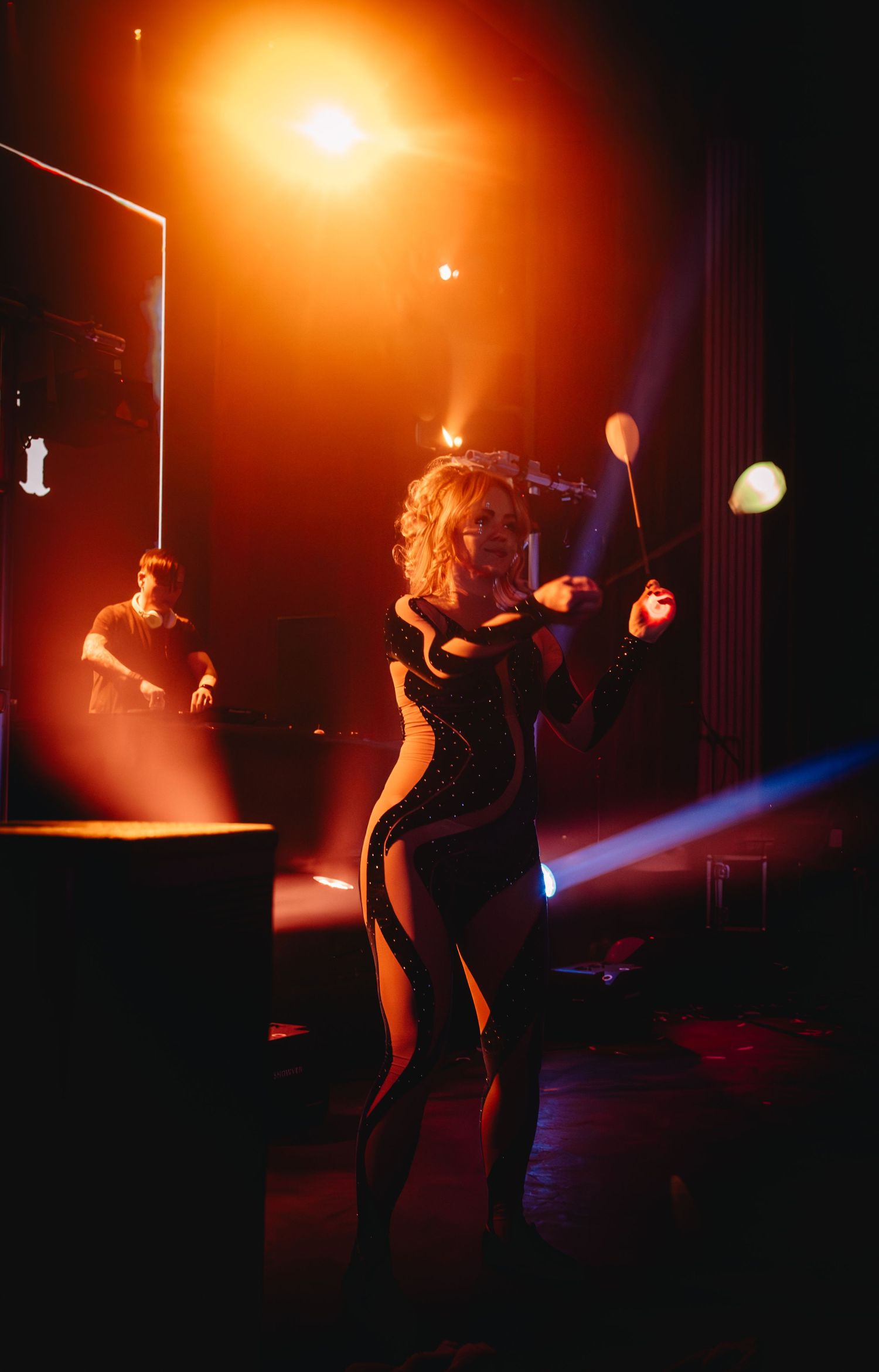 Silhouetted performer dancing on stage with warm orange lighting effects.