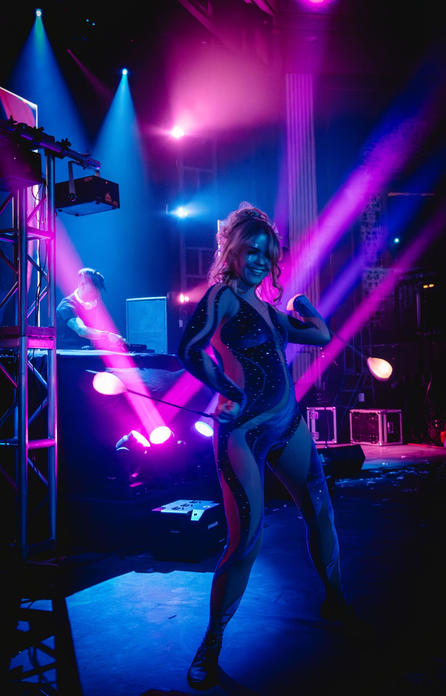 Dynamic stage performance with vibrant pink and blue theatrical lighting effects.