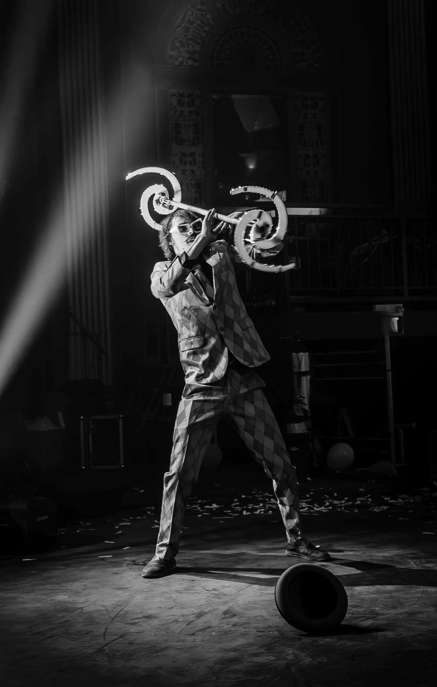 Black and white photo of performer spinning light tools in theatrical stage performance.