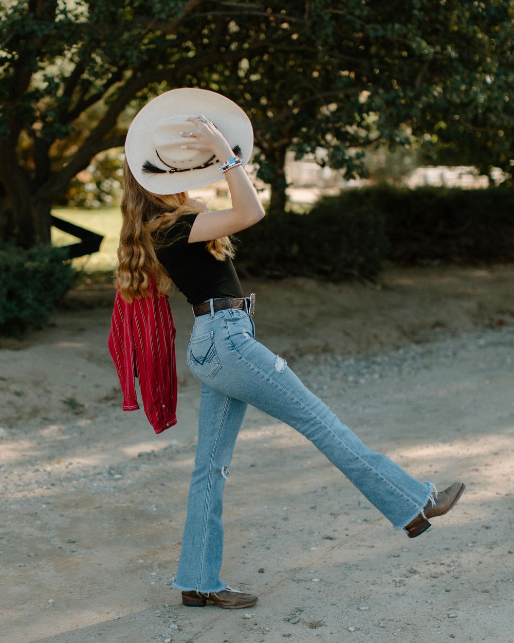A sequence of dance steps showing blue jeans and cowboy boots against a dirt path in warm sunlight.