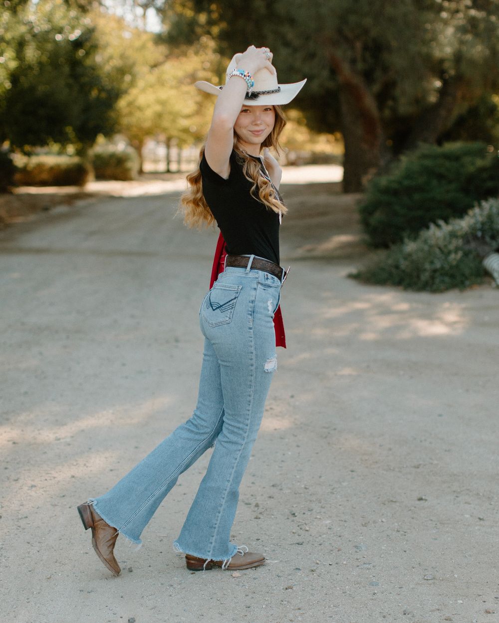 Western style dance movements captured in a series showing denim and boots on a sunny outdoor path.