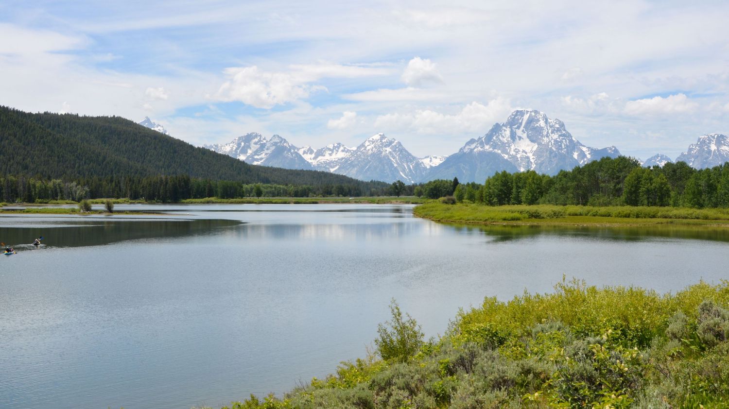 Scenic view of Snake River with snow-capped Grand Teton mountains in the background at Grand Teton National Park.