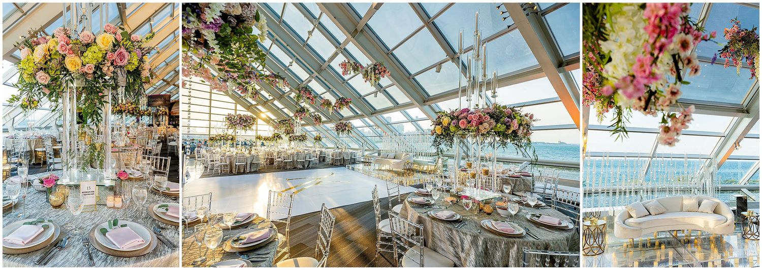 Light-filled glass venue decorated with hanging floral arrangements and elegant table settings.