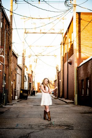 Urban alleyway portrait with sunlit brick walls and hanging power lines creating dramatic atmosphere.