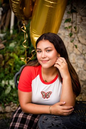 Close-up portrait with gold balloons featuring red baseball tee and leopard print butterfly design.