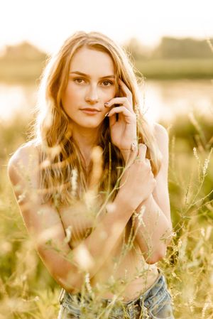 Dreamy golden hour portrait in a field of tall grass with soft natural lighting.