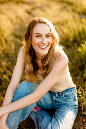 Person in casual outfit sitting in a sunlit field of golden grass.