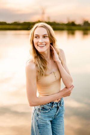 Portrait in casual attire against sunset lake backdrop.