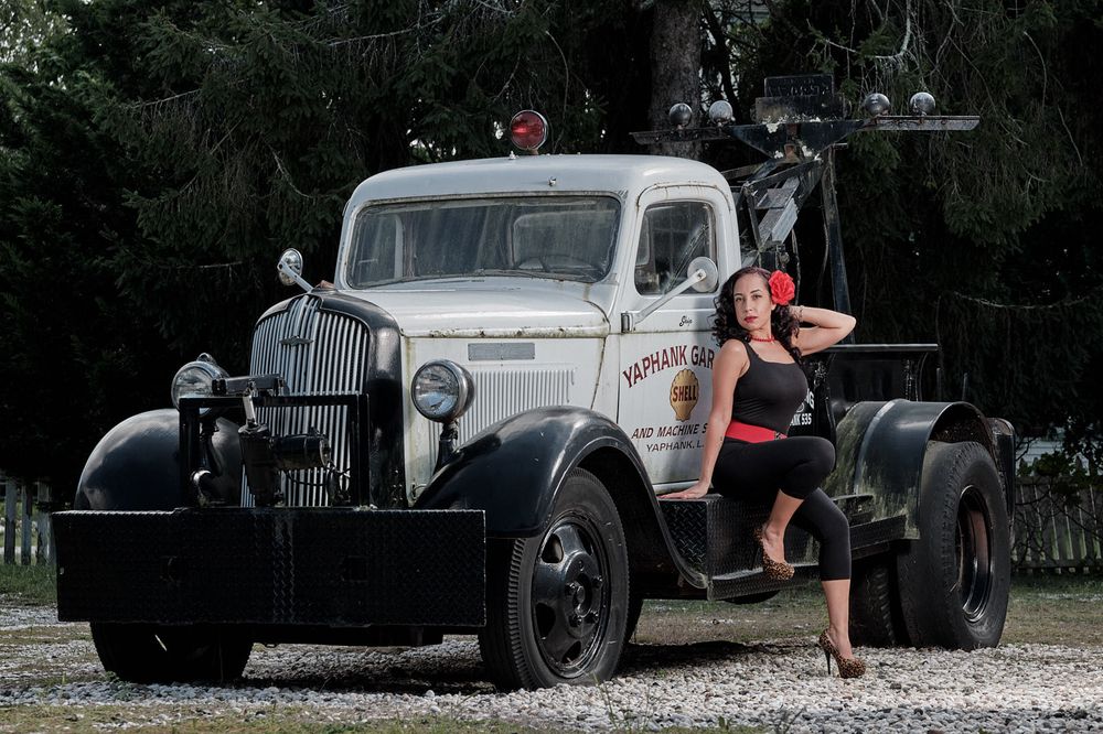 Vintage tow truck serves as backdrop for retro-styled photo shoot outdoors.