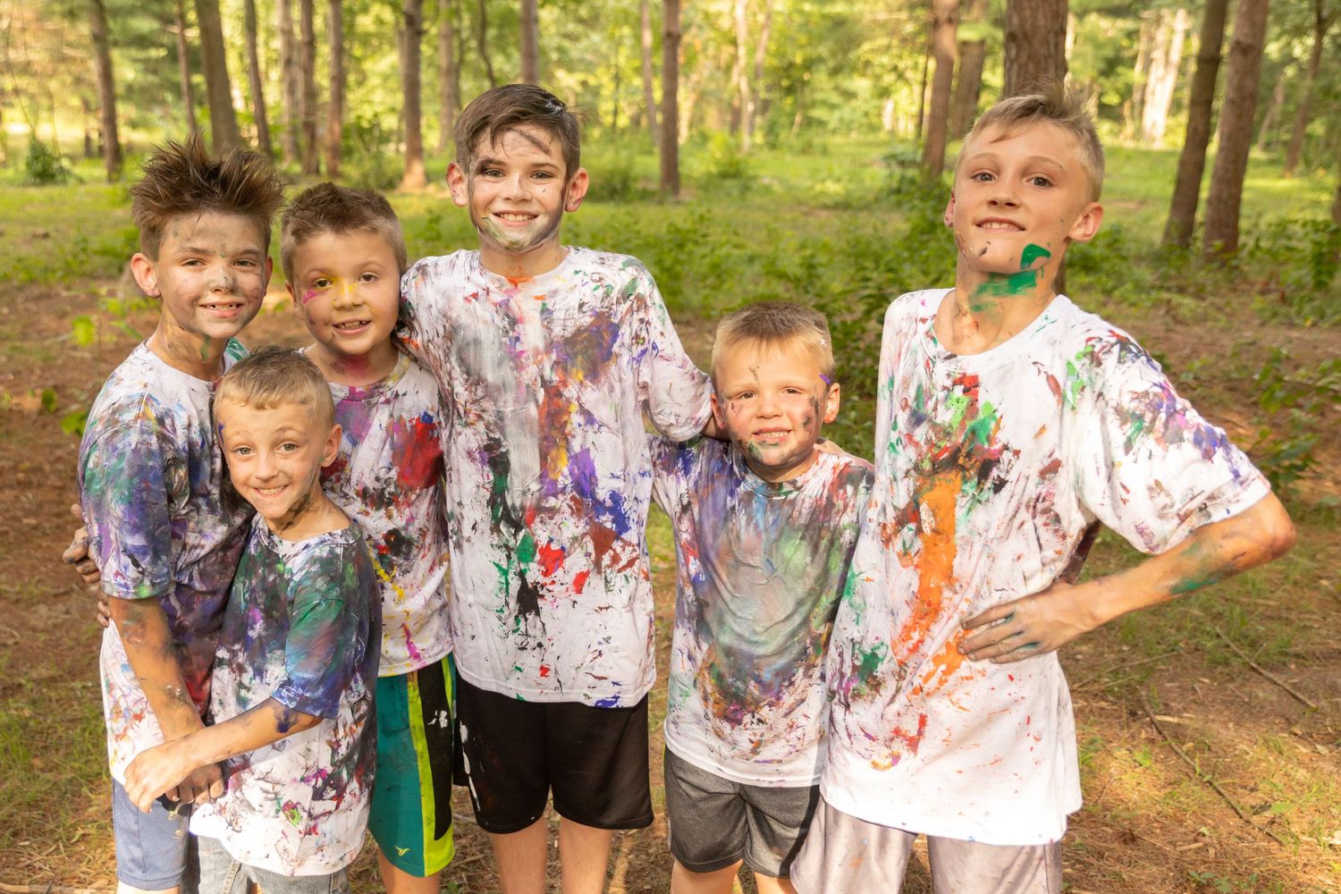A group of young boys covered in paint smears, smiling happily.