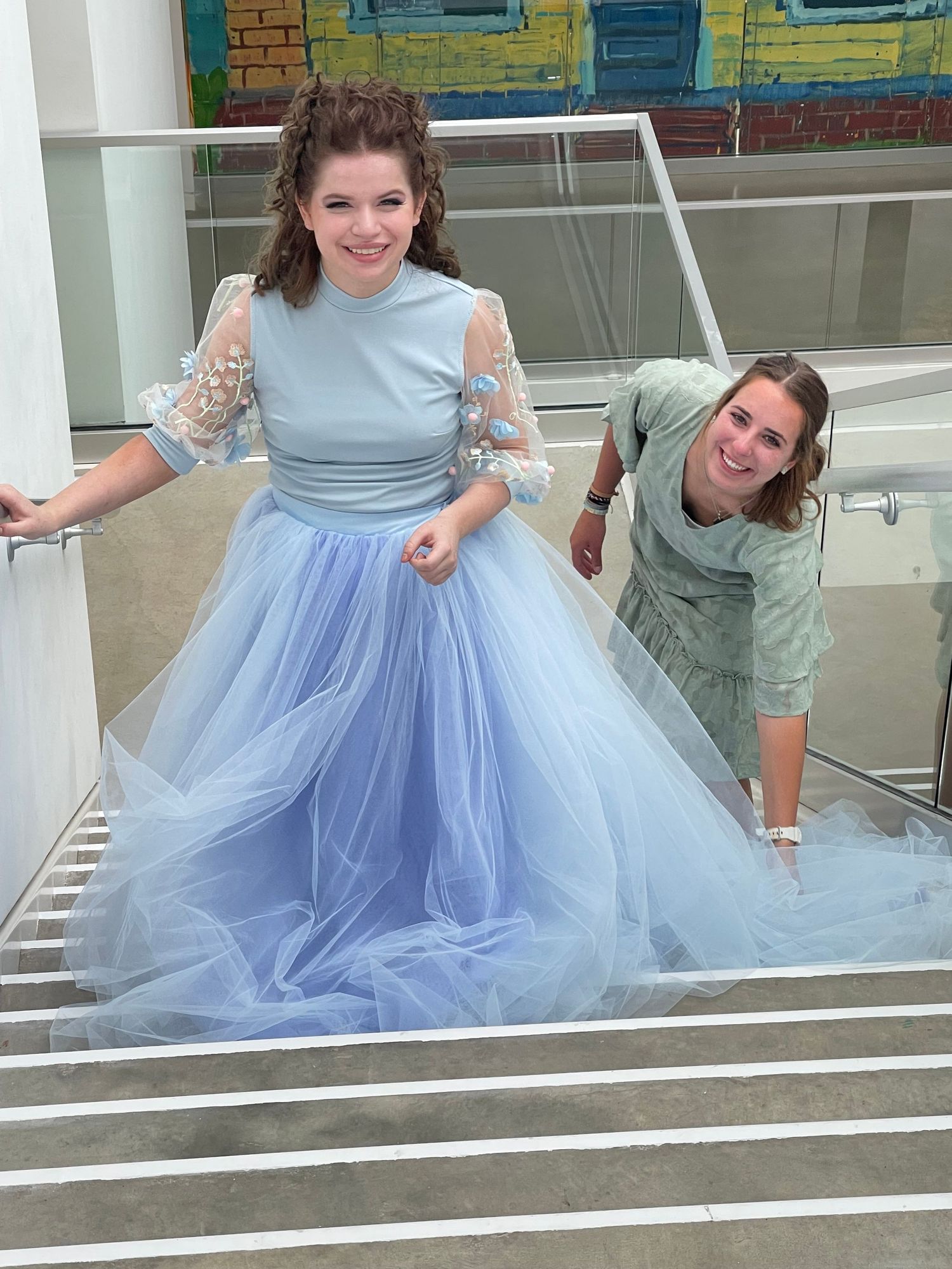Playful moment on stairs with flowing blue tulle dress during photo session.