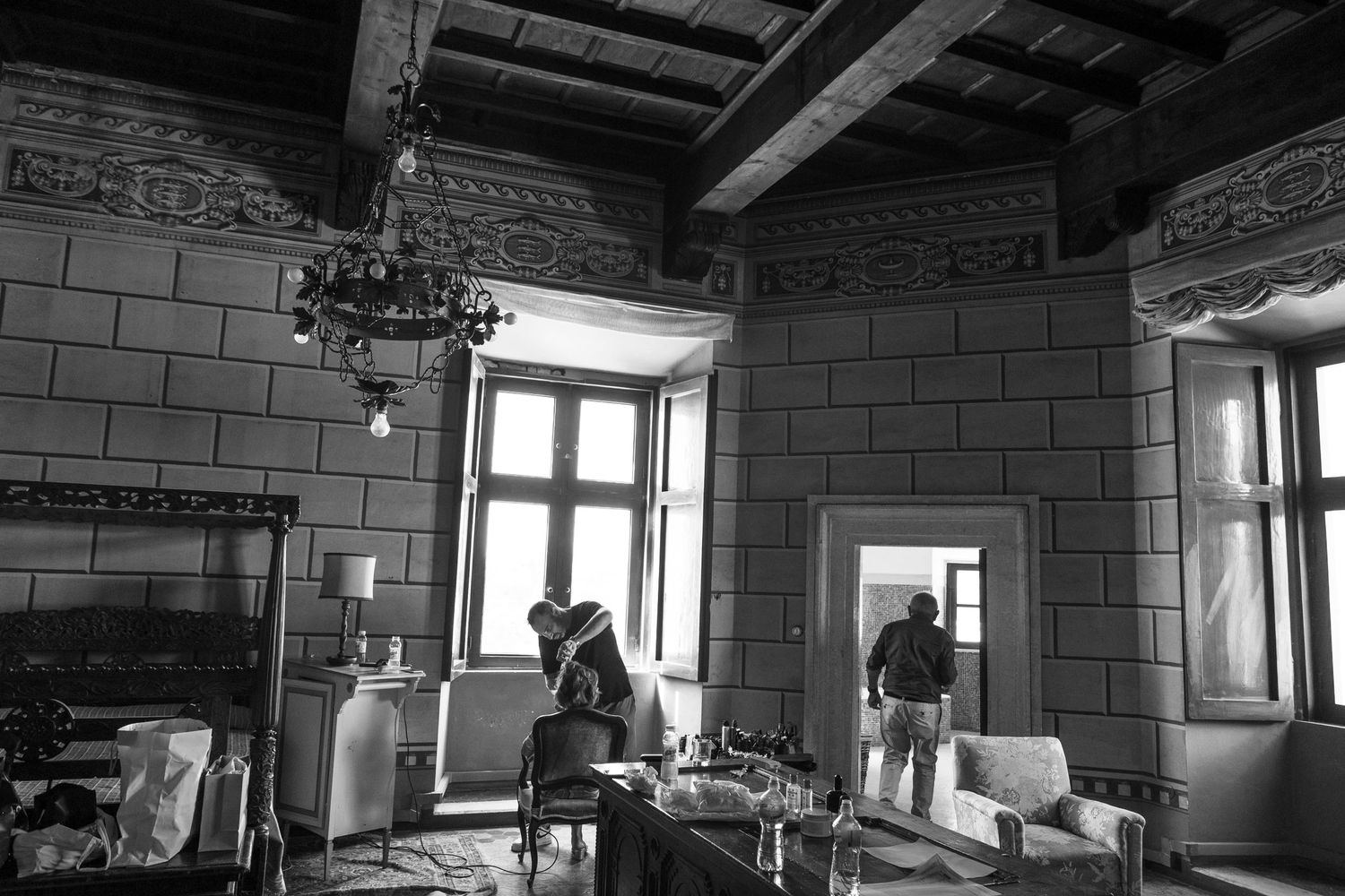 Black and white photograph of a rustic room with stone walls and large windows.