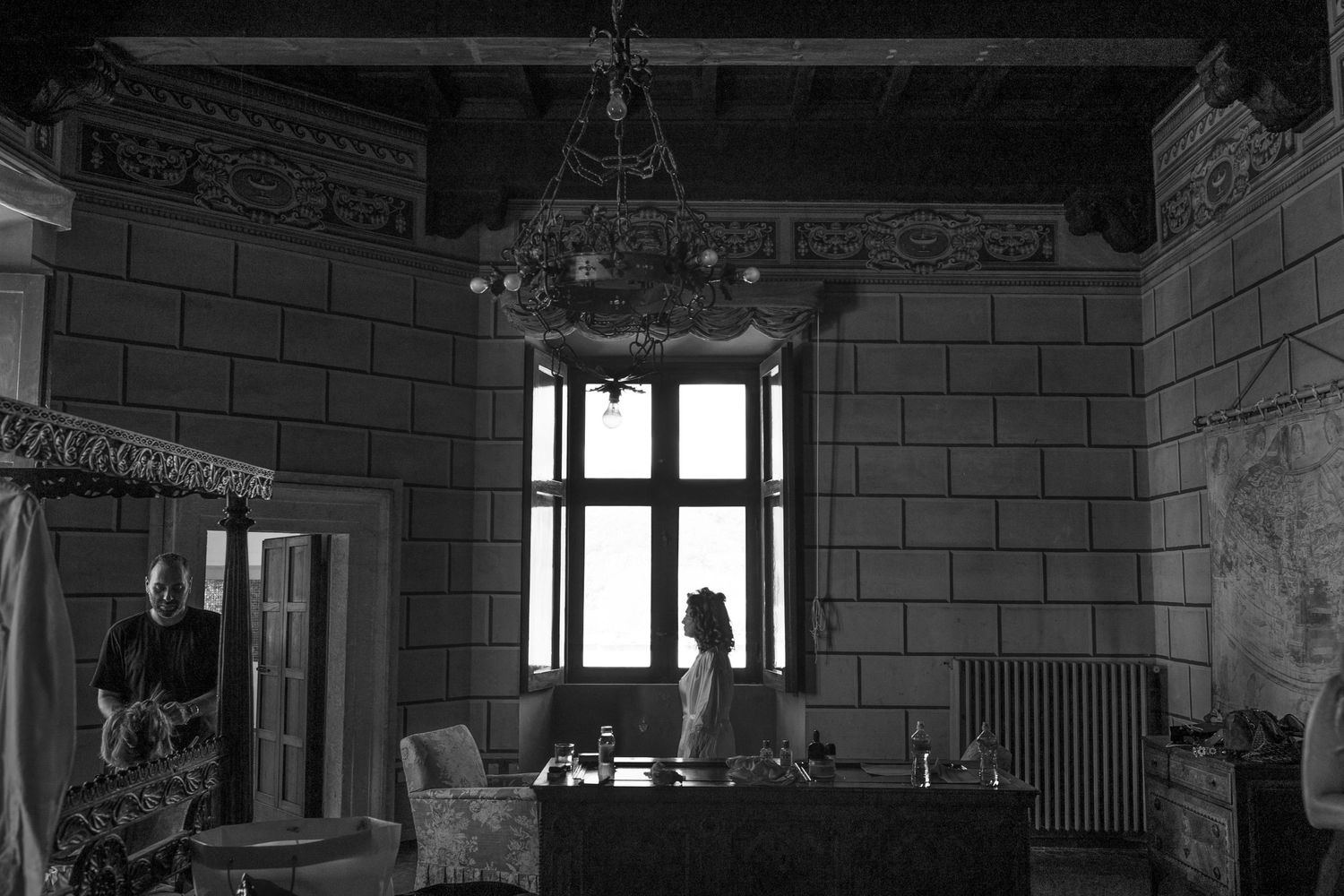 Moody black and white interior shot of a historic room with tall windows and stone walls.