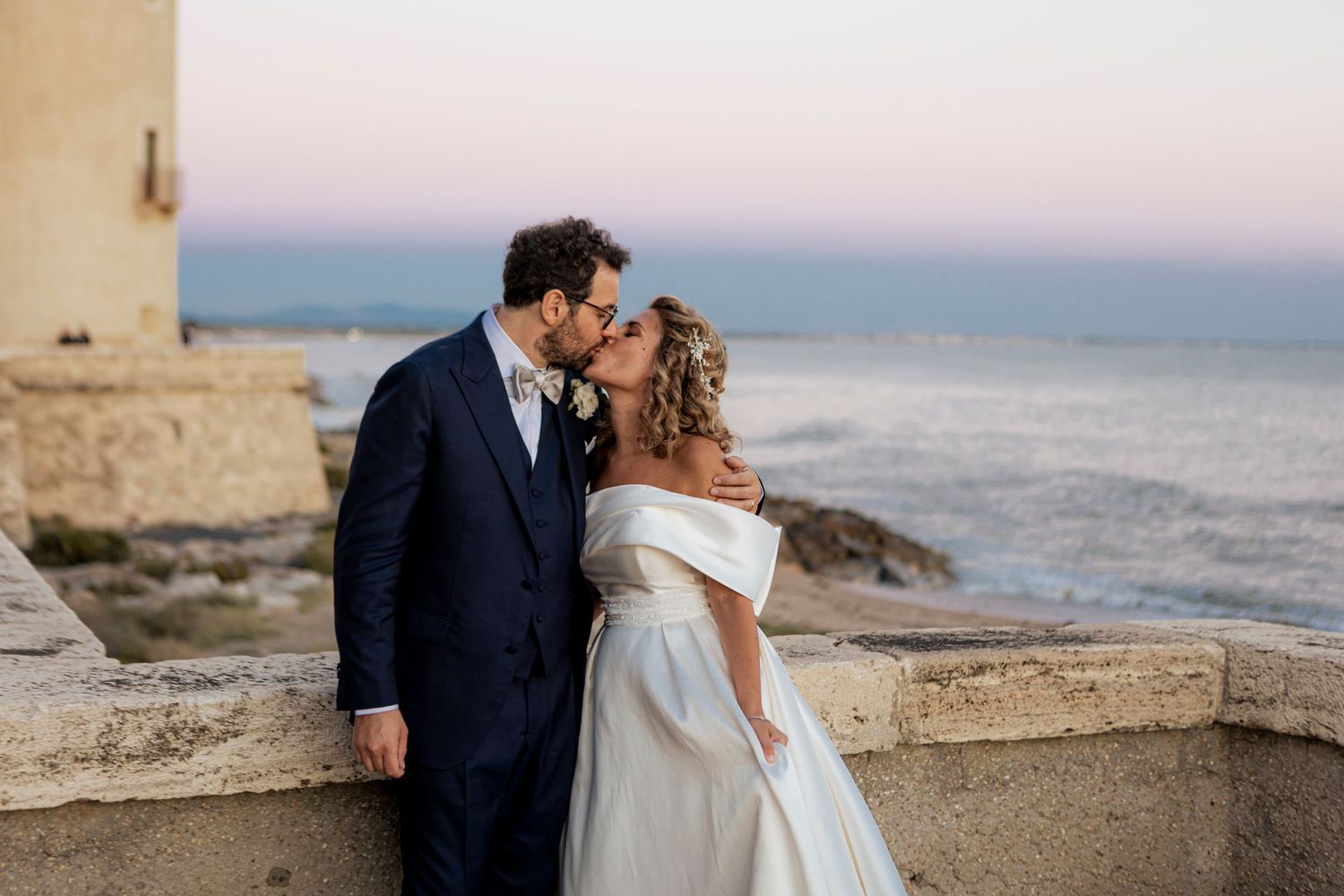 Romantic sunset portrait of newlyweds at a coastal venue.