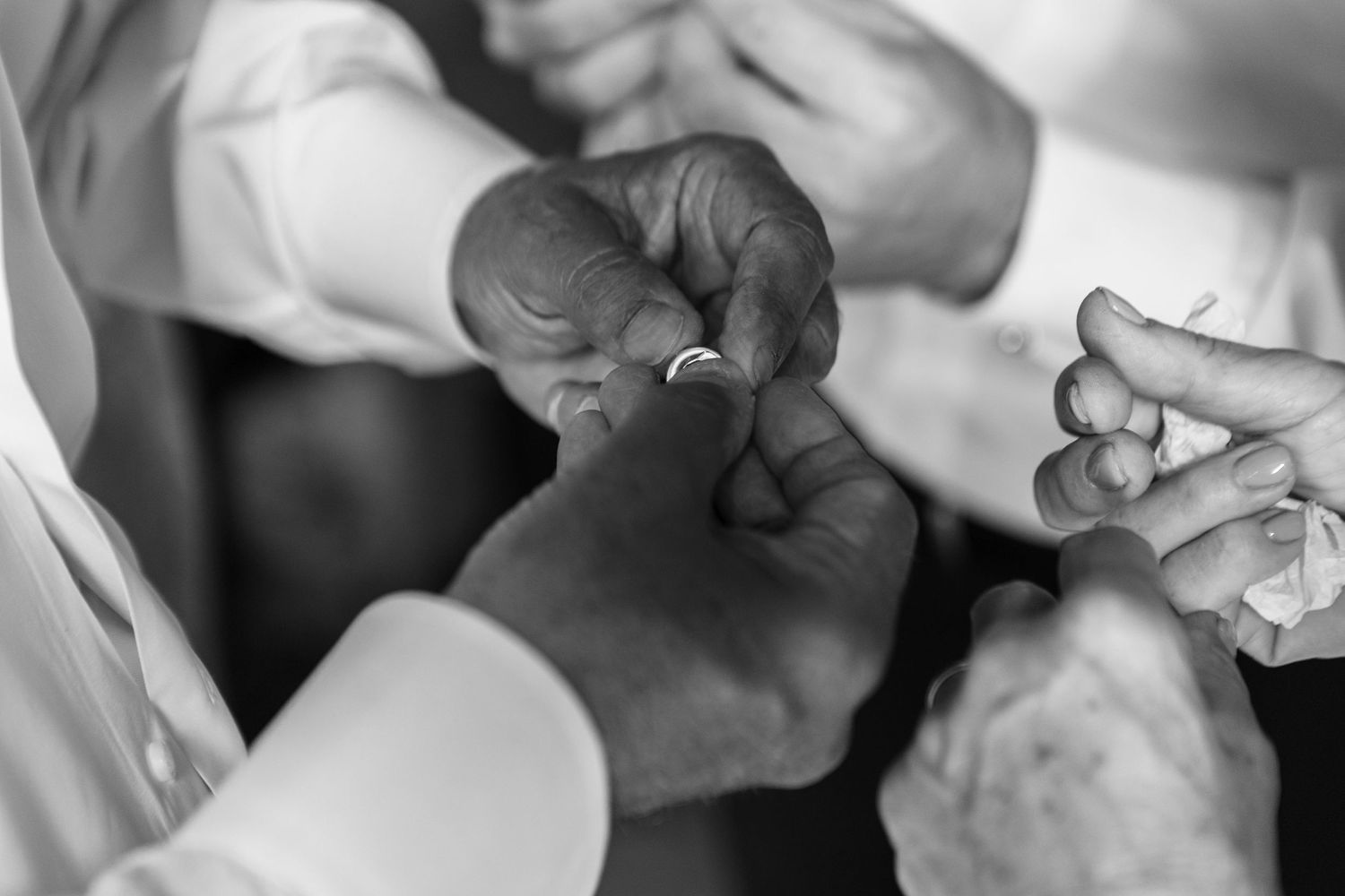 Close-up black and white image of hands working with delicate jewelry.