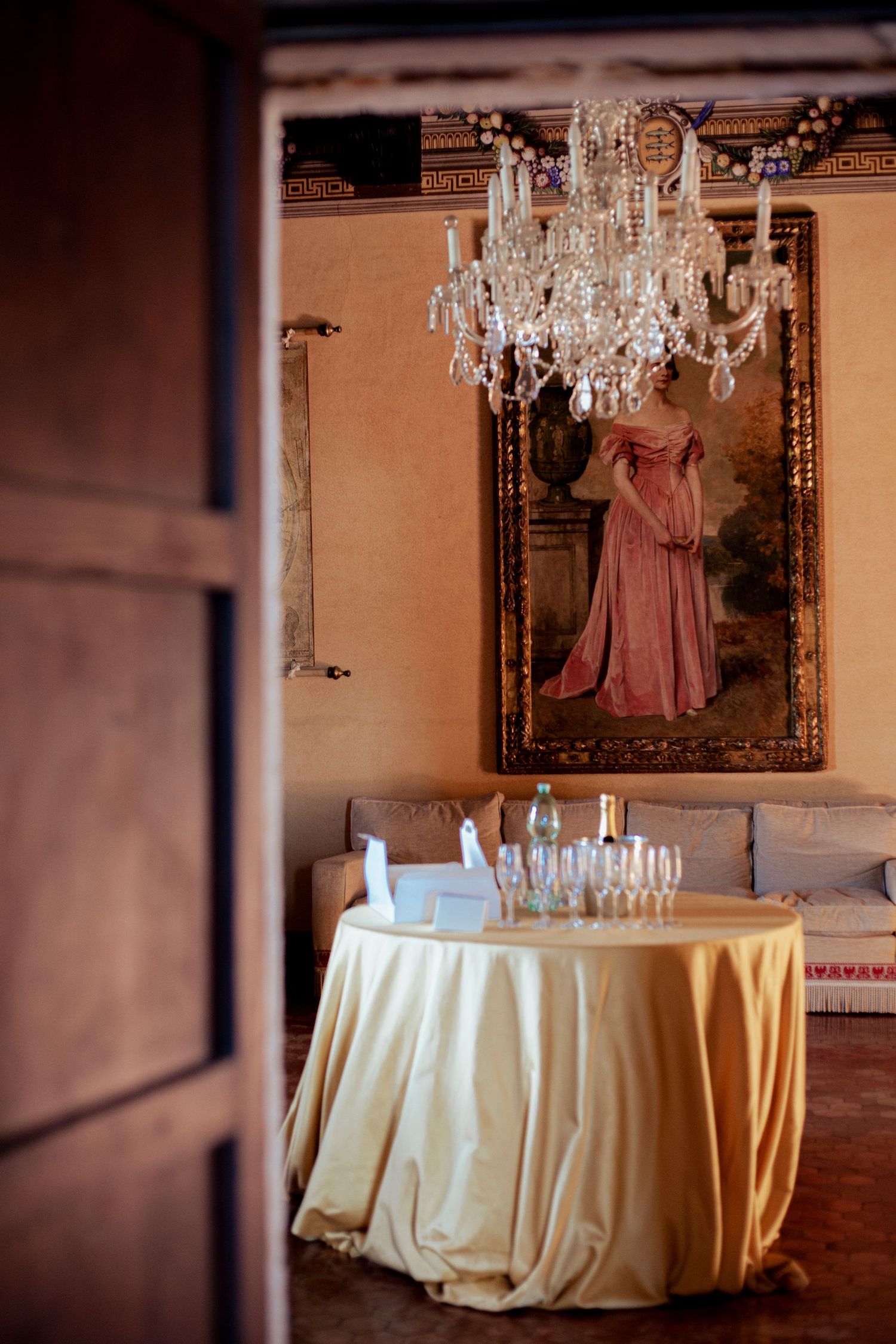 Elegant table setting with crystal chandelier and vintage portrait in classic reception room.