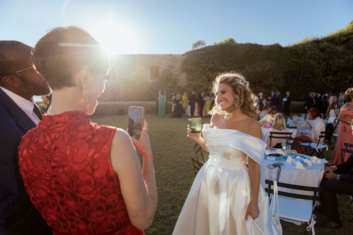 Wedding celebration at sunset with guests mingling on a lawn.