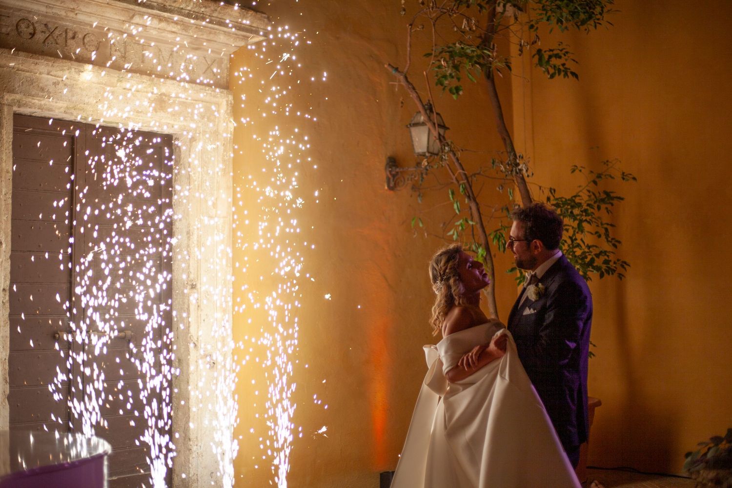 A wedding couple stands before dramatic sparklers during their reception celebration.
