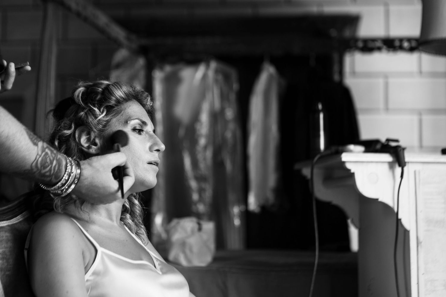 Behind the scenes shot of makeup and hair styling preparation in a black and white setting.