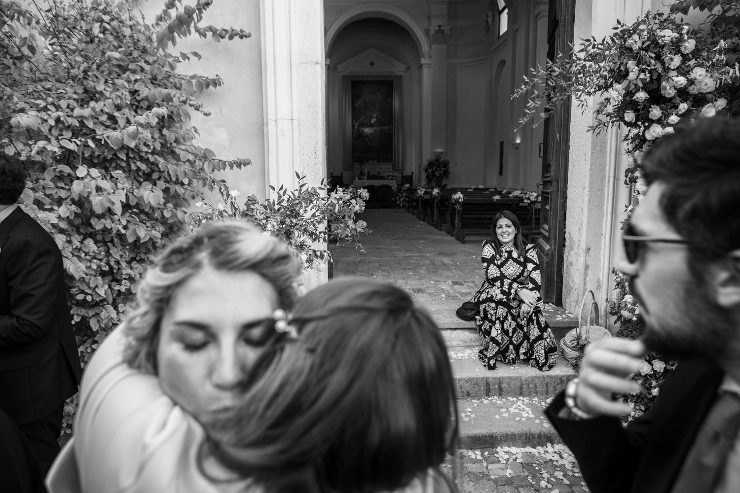 Intimate black and white candid moment captured during outdoor wedding celebrations.