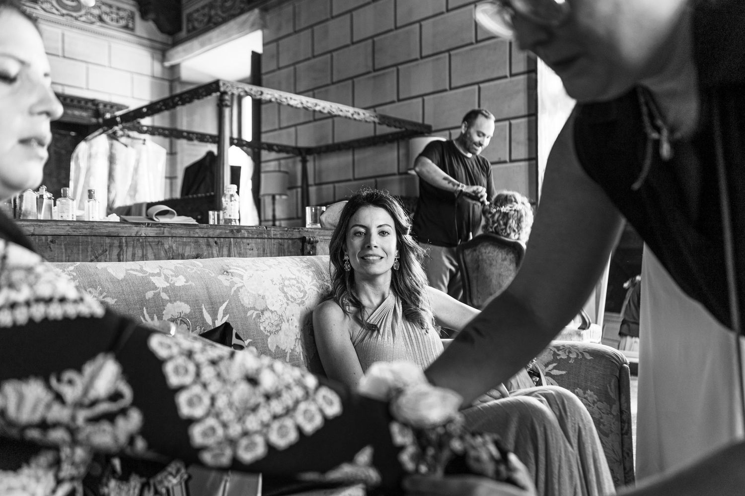 Candid black and white image showing wedding preparation moments in a rustic interior setting.