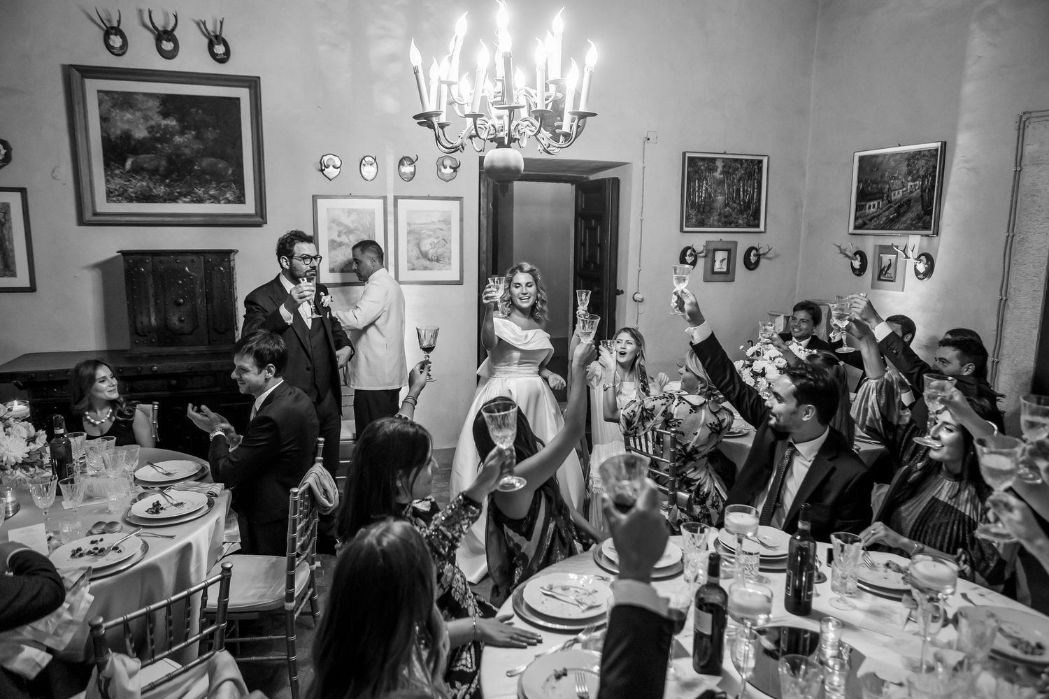 Black and white shot of wedding guests celebrating at an elegant dinner reception.