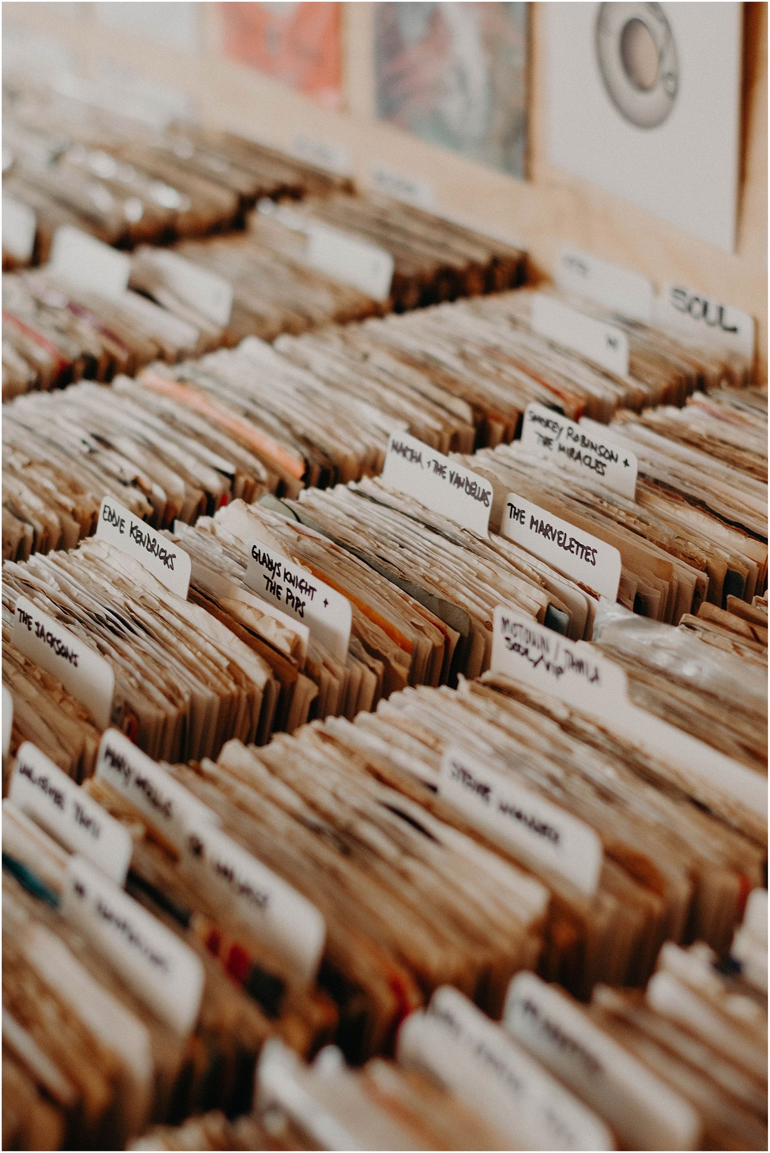 Organized rows of vinyl records in a record store with labeled dividers for browsing.