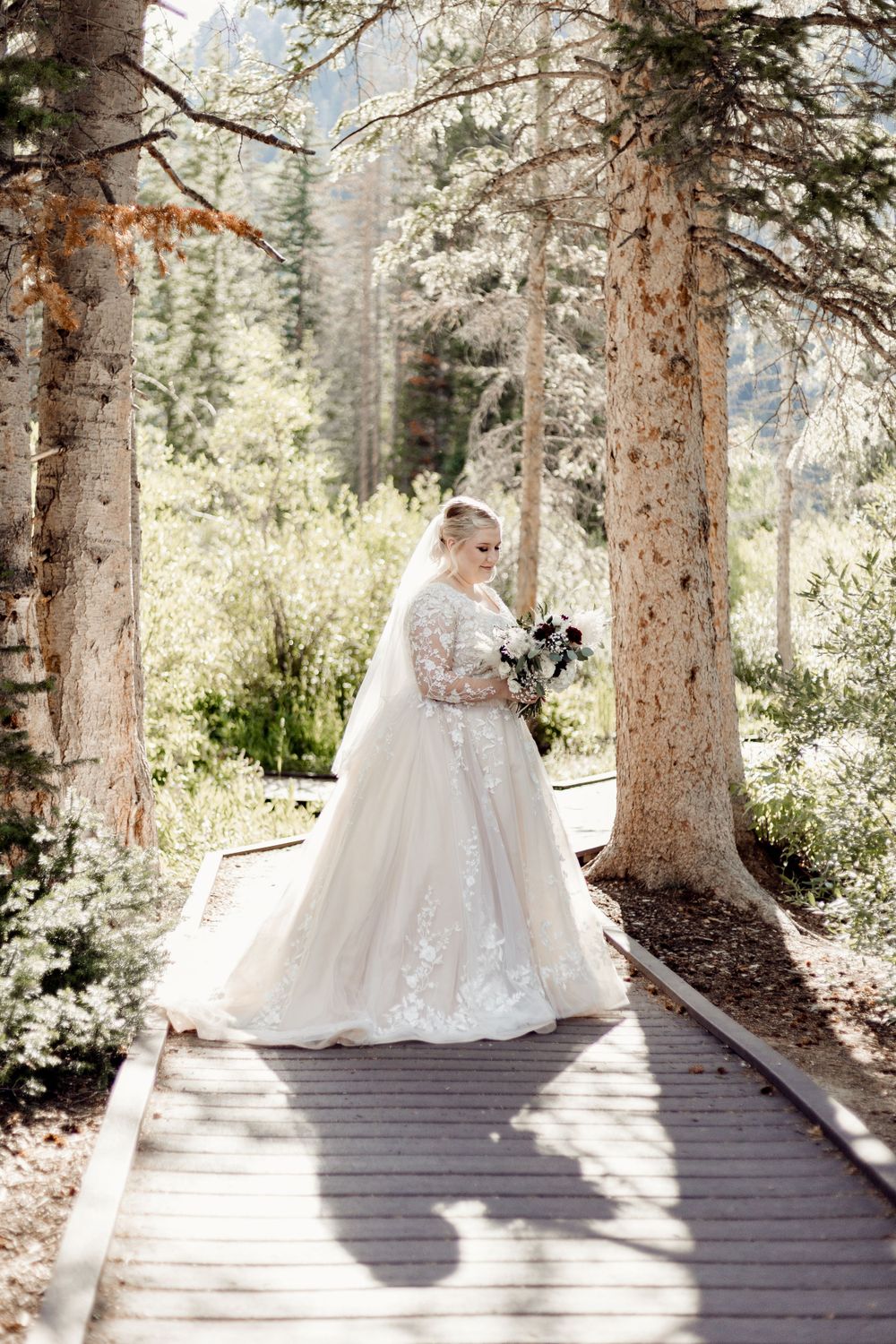 elegant bride gazing at wedding bouquet in missouri forest