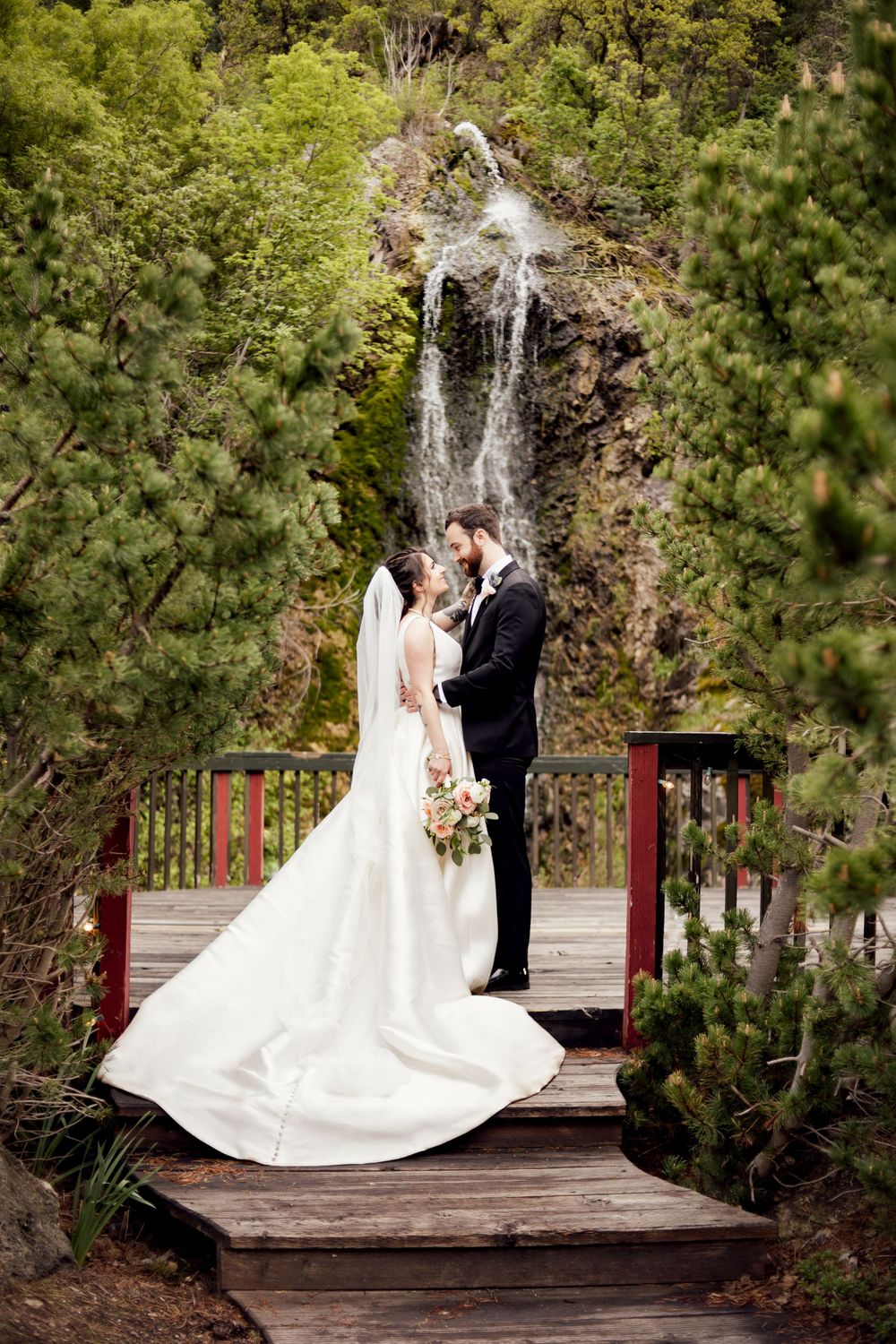 black tie bride and groom looking lovingly into each others eyes by a waterfall photographed by missouri wedding photographer