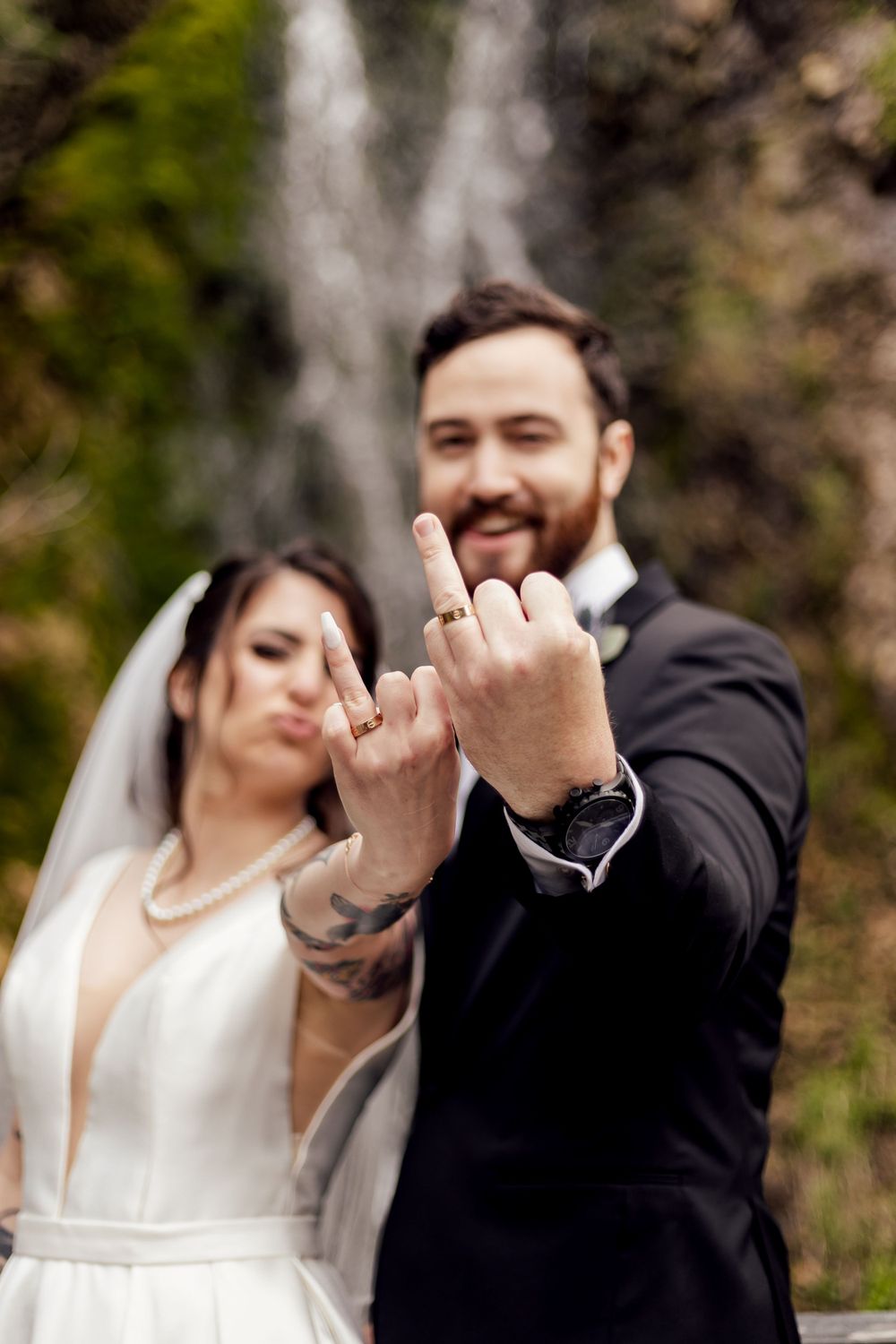 fun couple showing wedding rings by a waterfall photographed by missouri photographer