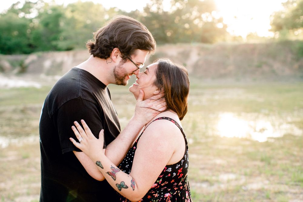 Intimate couple embracing outdoors near a pond at sunset.