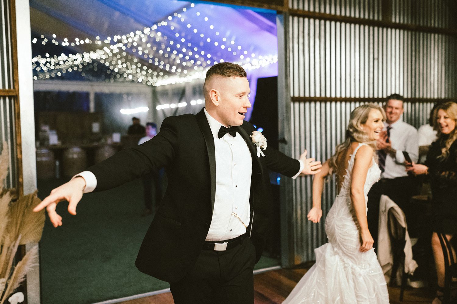 Wedding reception dance floor scene with string lights and celebrating guests.