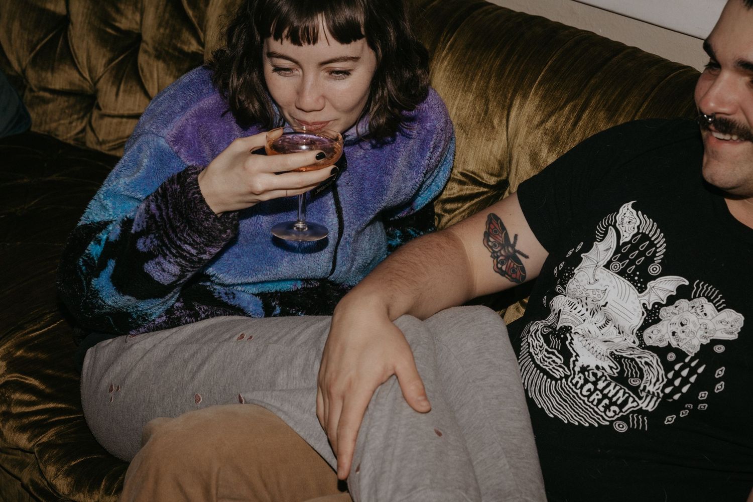 Candid moment of two people relaxing on leather couch with wine.