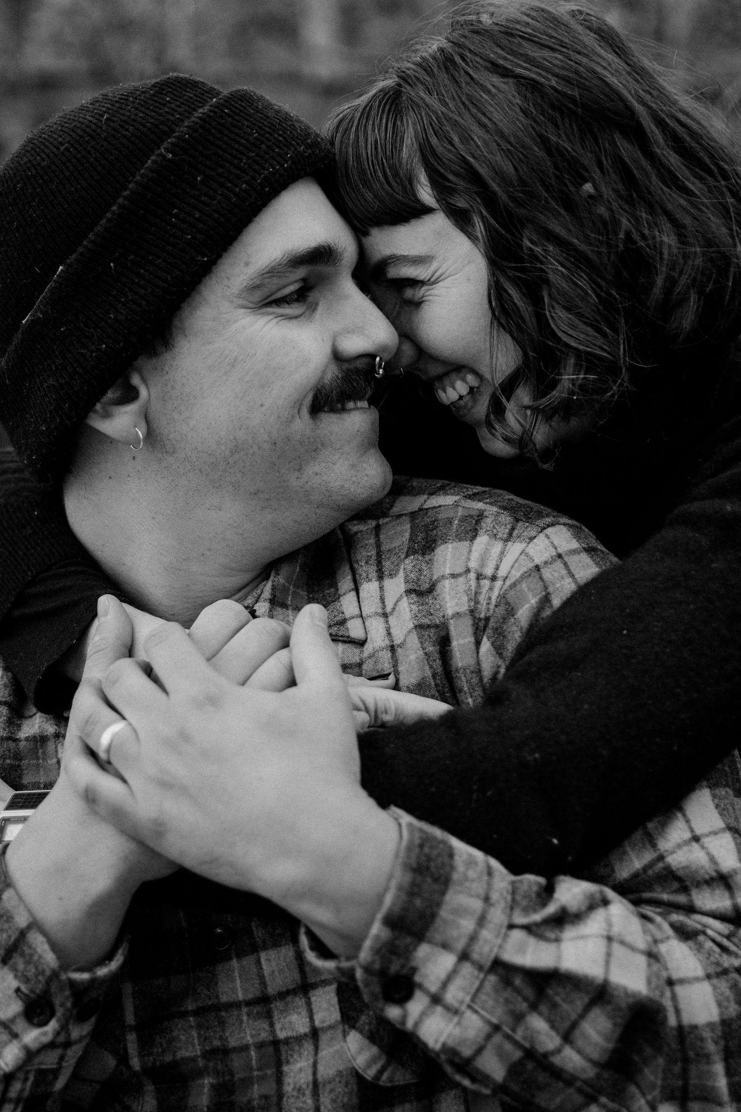 An intimate black and white portrait showing a couple in a close embrace with genuine laughter.