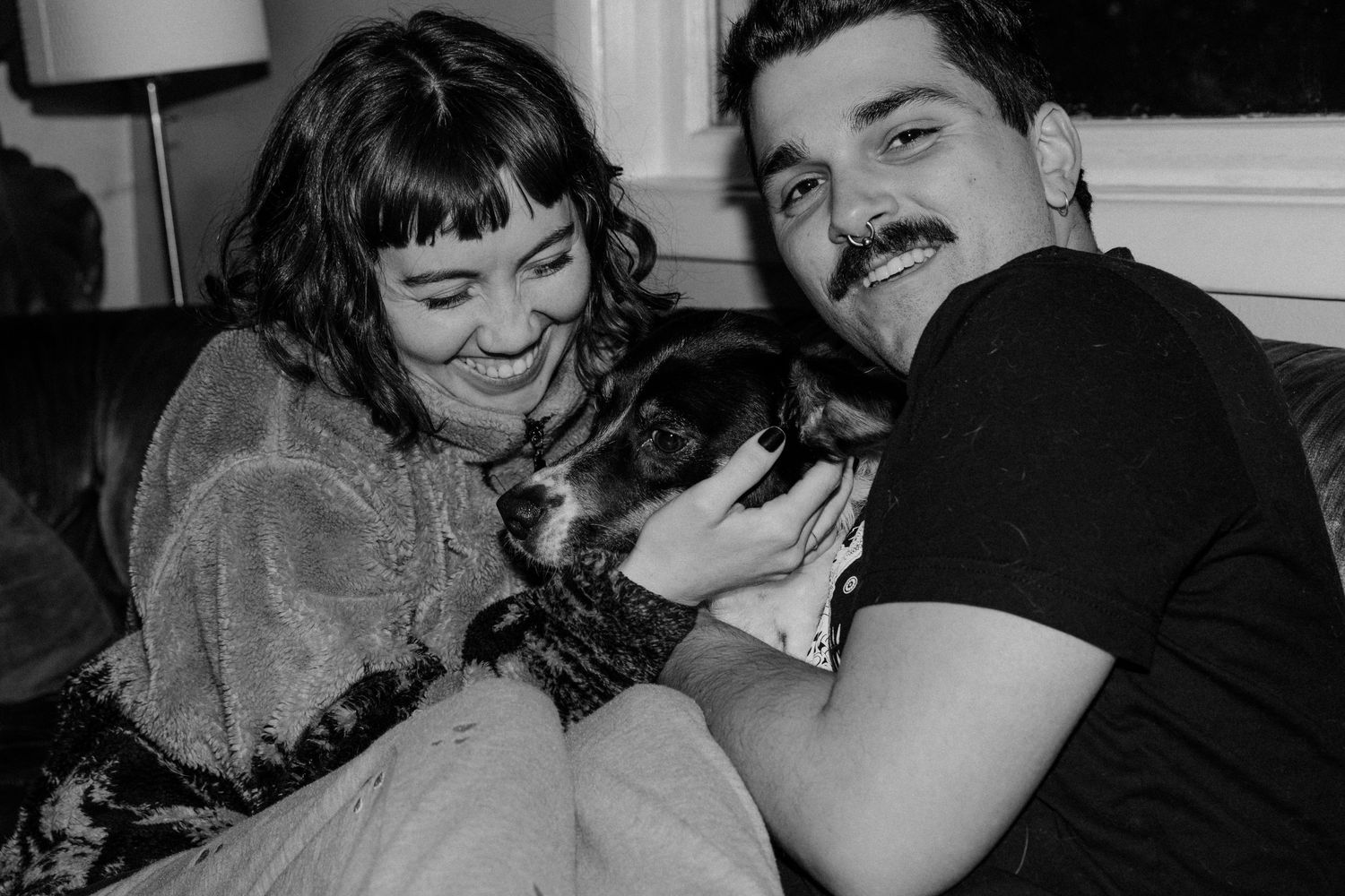 Black and white image showing a tender moment with a pet cat on a couch.