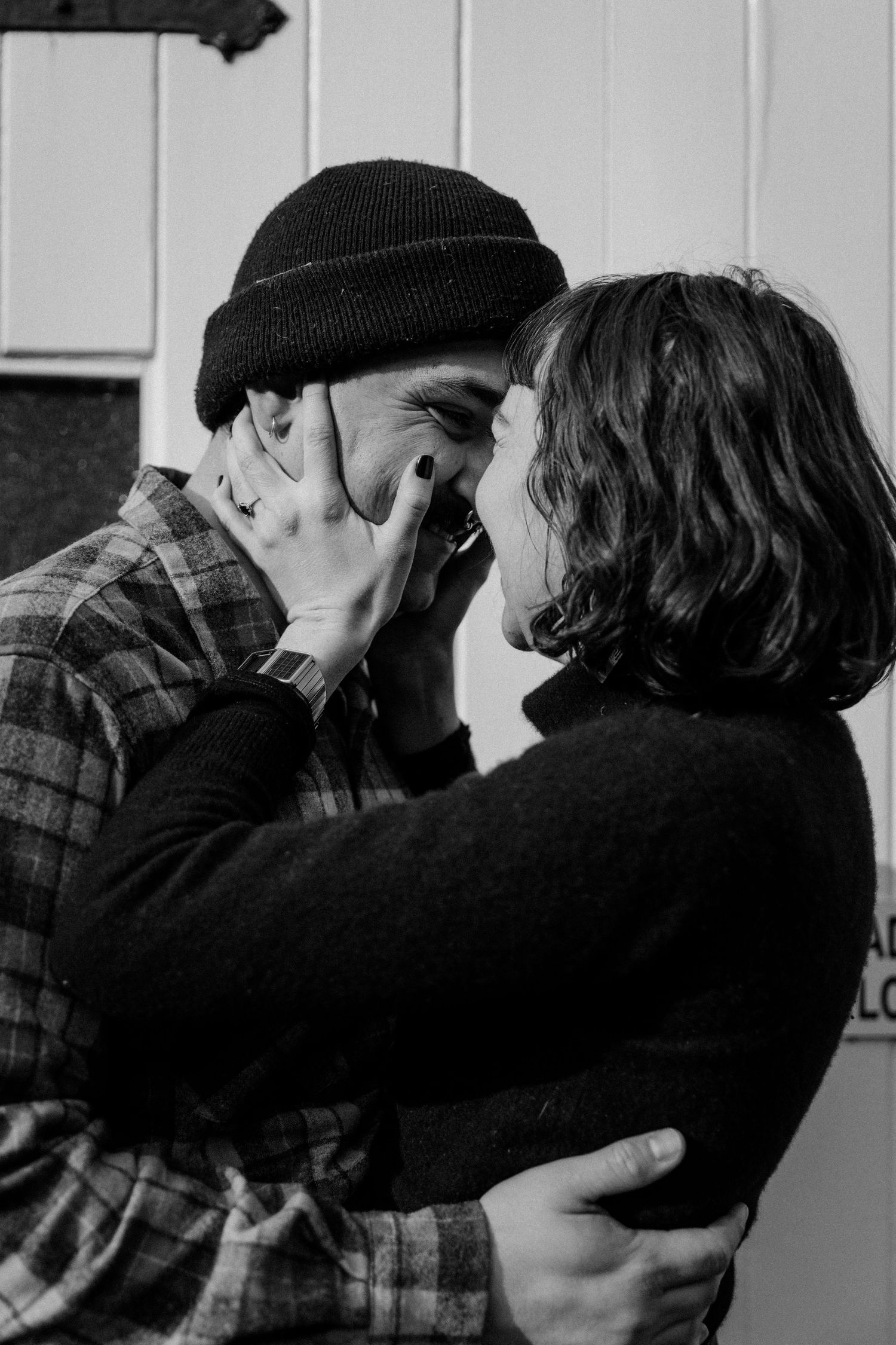 An intimate black and white portrait of a couple sharing a tender moment outdoors.