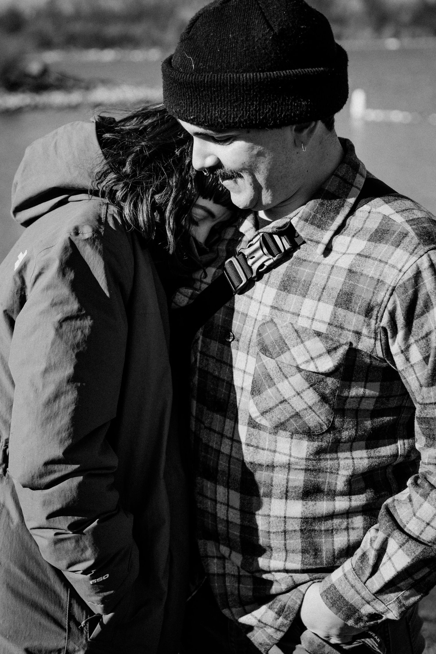 Winter scene showing tender moment between two people in plaid and winter clothing.