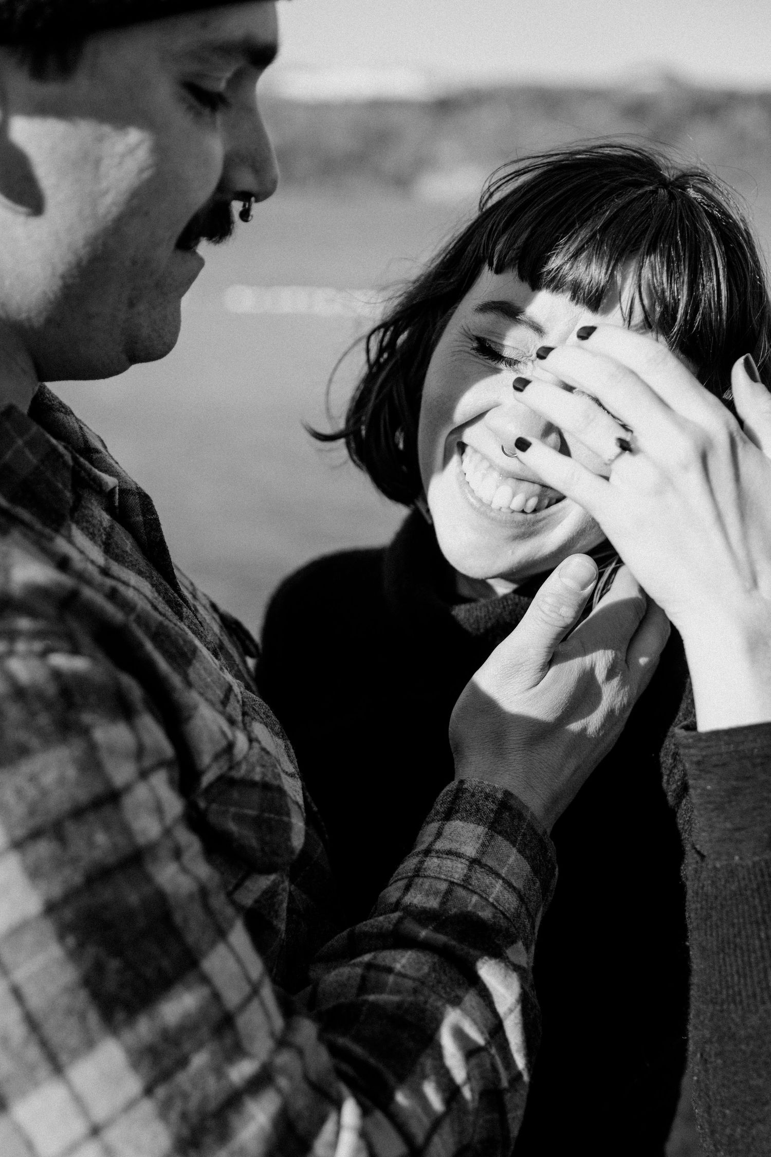 Candid moment of laughter and joy between a couple in black and white photography.
