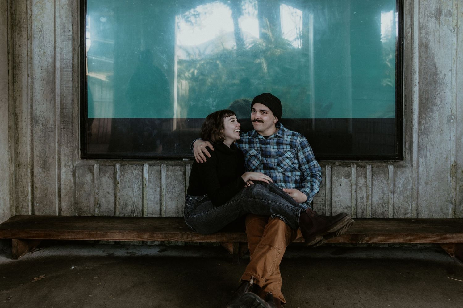 A couple sitting together on a bench in front of an aquarium display.